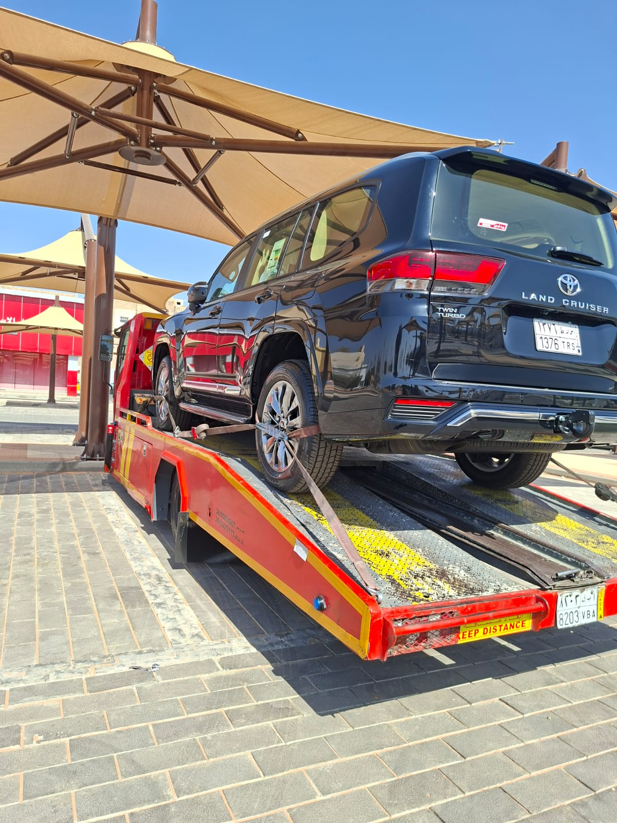 سطحة نقل سيارات تنقل تويوتا لاندكروزر سوداء VIP في الخبر